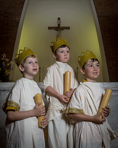 Image of three students in church holding candles