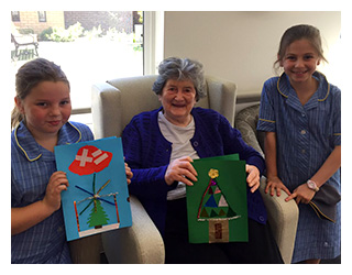 St Aloysius School students with a resident from Sheridan Hall showing their handmade Christmas cards