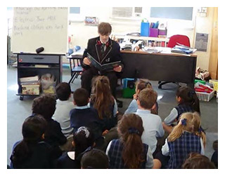 Image of a secondary school student reading to primary school students